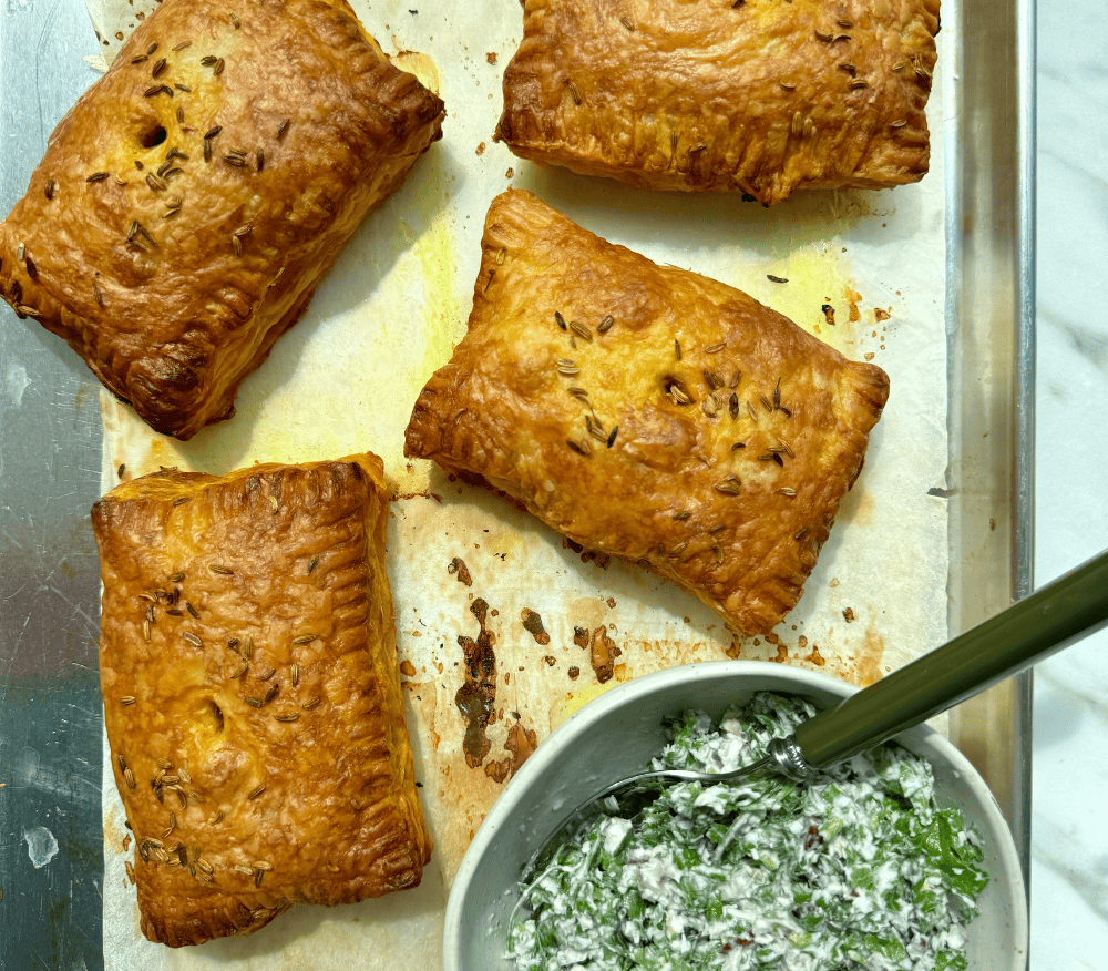 Four spiced chickpea pastry parcels on a baking tray